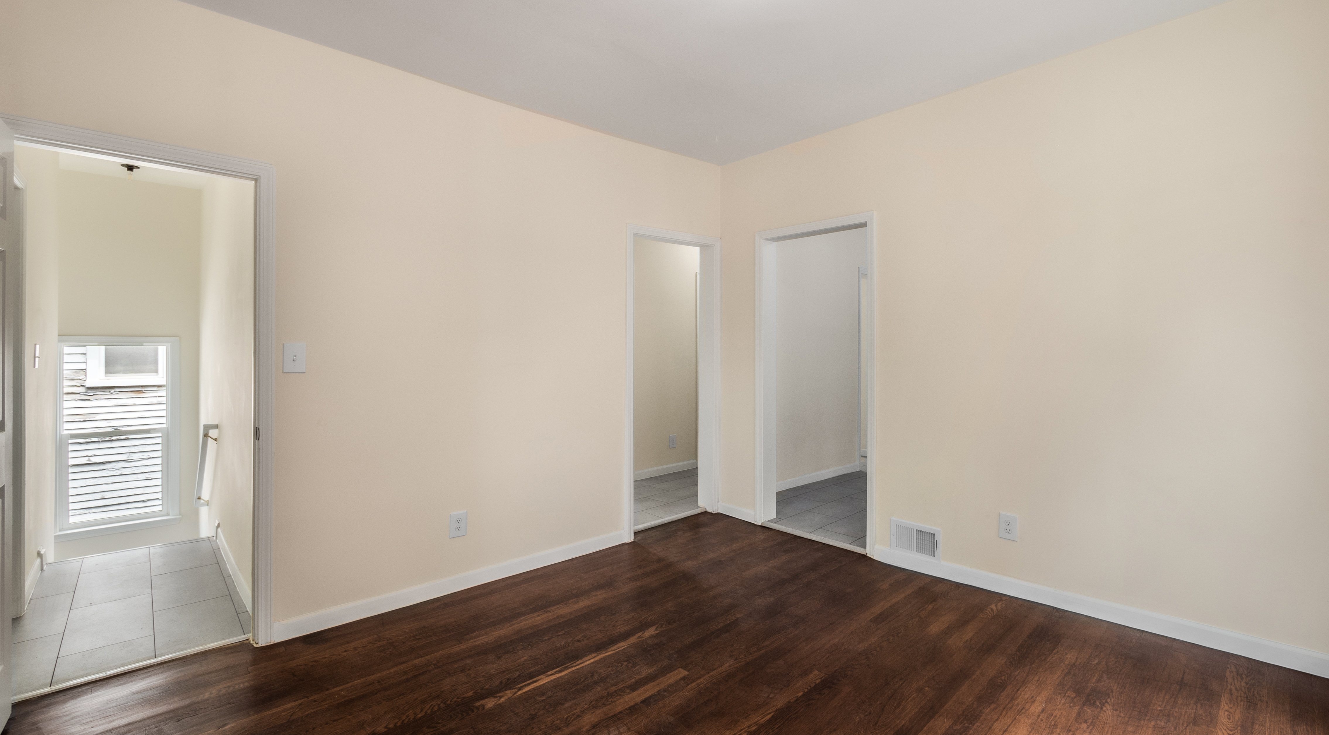 A room with wooden floors and two doors.